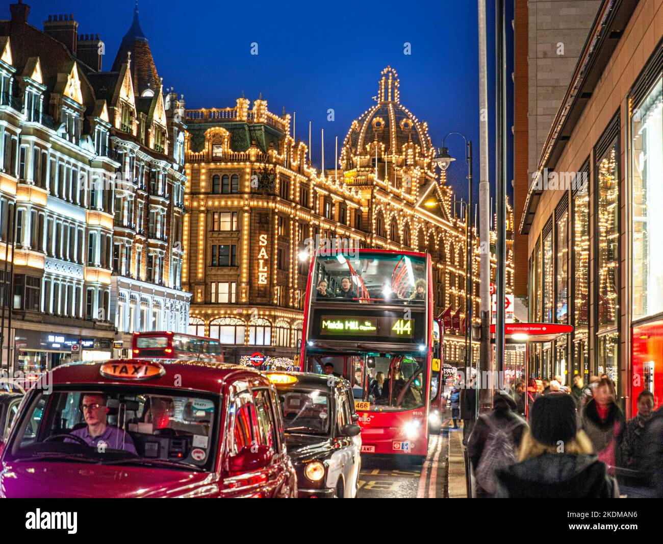 KNIGHTSBRIDGE TRAFFICO VENDITA INVERNALE Harrods grande magazzino di notte illuminato 'sale' segno shoppers rosso autobus, taxi, traffico sfocato Brompton Road Knightsbridge Londra SW1 Foto Stock