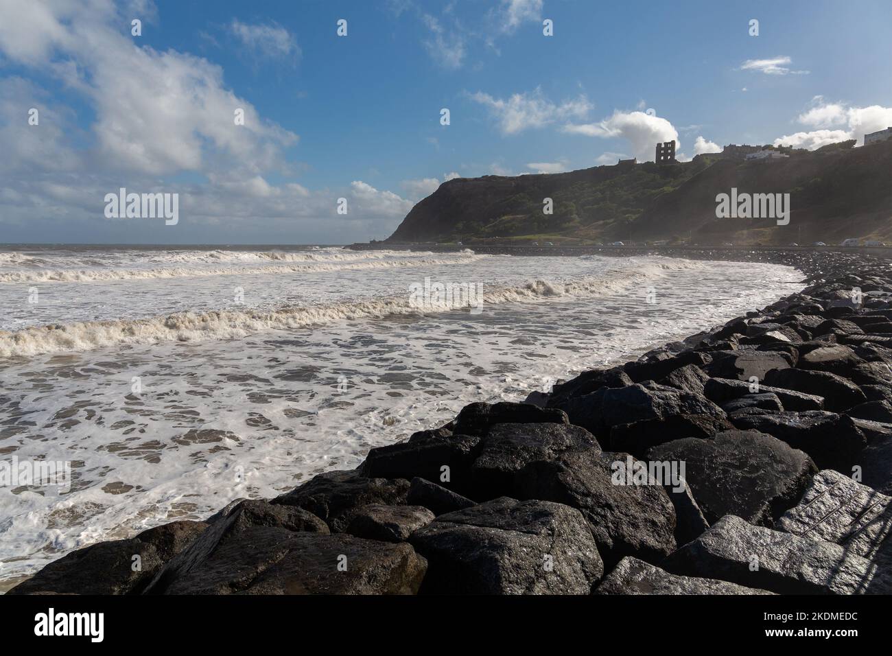 Scarborough, Regno Unito: Mari tempestosi in alta marea sulla costa della North Bay, con il famoso castello sulla scogliera della città dello Yorkshire sullo sfondo Foto Stock