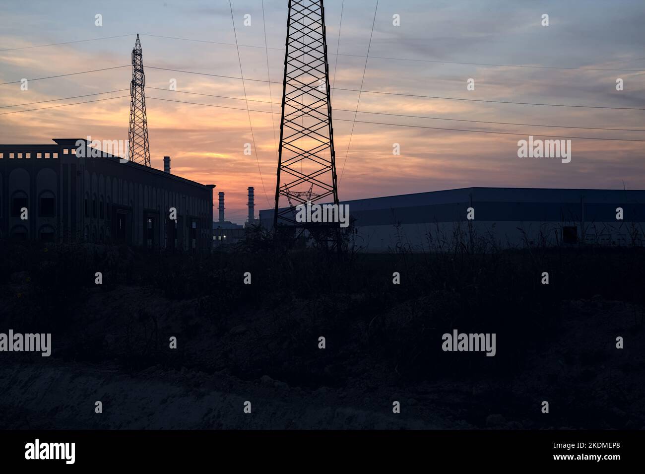 Magazzini abbandonati e un pilone alla periferia di una città italiana al tramonto Foto Stock