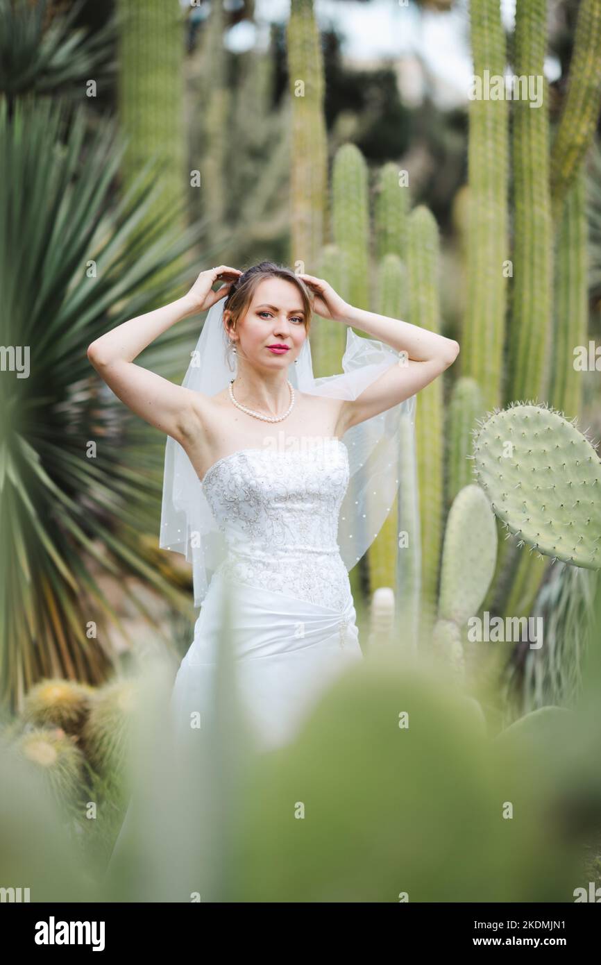 Sposa circondata da piante di Cactus in un giardino nel tardo pomeriggio Foto Stock