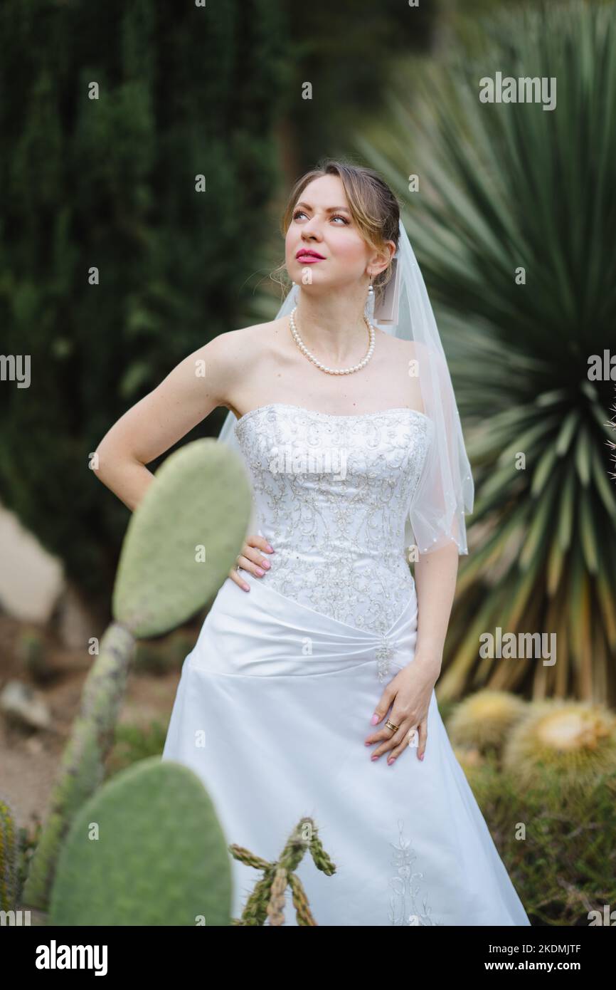 Sposa circondata da piante di Cactus in un giardino nel tardo pomeriggio Foto Stock