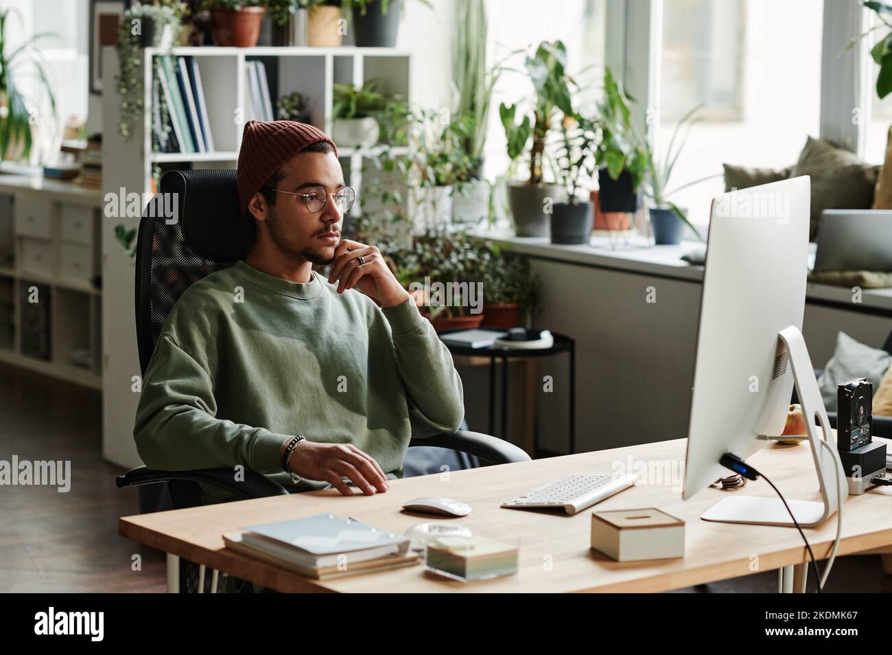 Giovane uomo d'affari serio che guarda lo schermo del computer mentre guarda video online o in attesa di caricamento della pagina del sito web Foto Stock