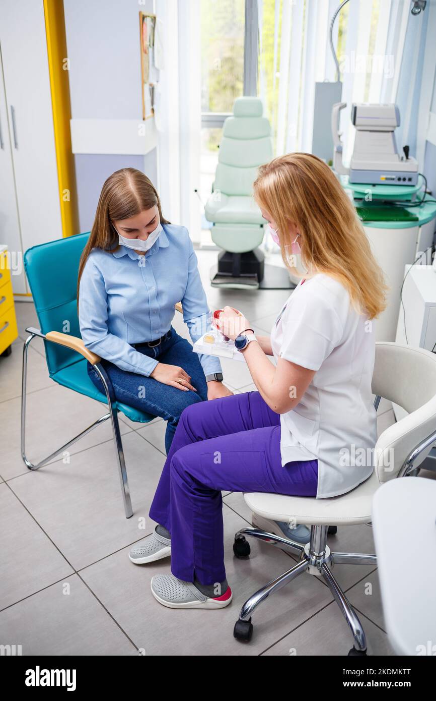 Giovane donna seduta in poltrona guardando la lampada a fessura durante l'esame medico negli occhi Foto Stock