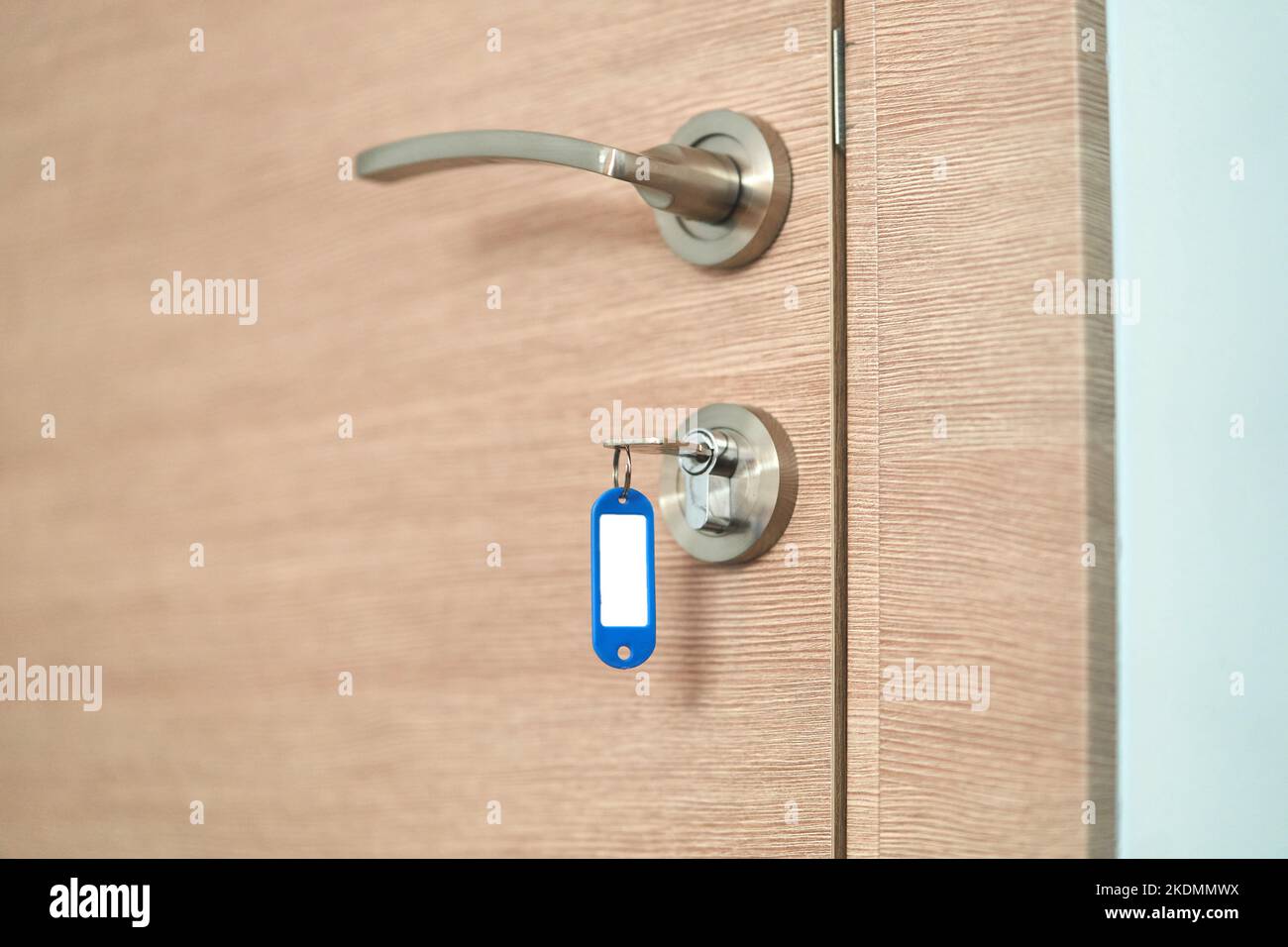 Una chiave con un portachiavi vergine nella serratura di una porta di legno vicino Foto Stock