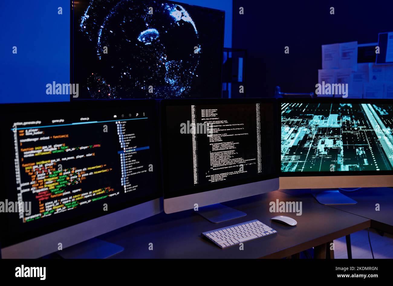 Fila di tre monitor per computer con dati codificati su schermi in piedi su orkplace di diversi ingegneri O programmatori IT moderni Foto Stock