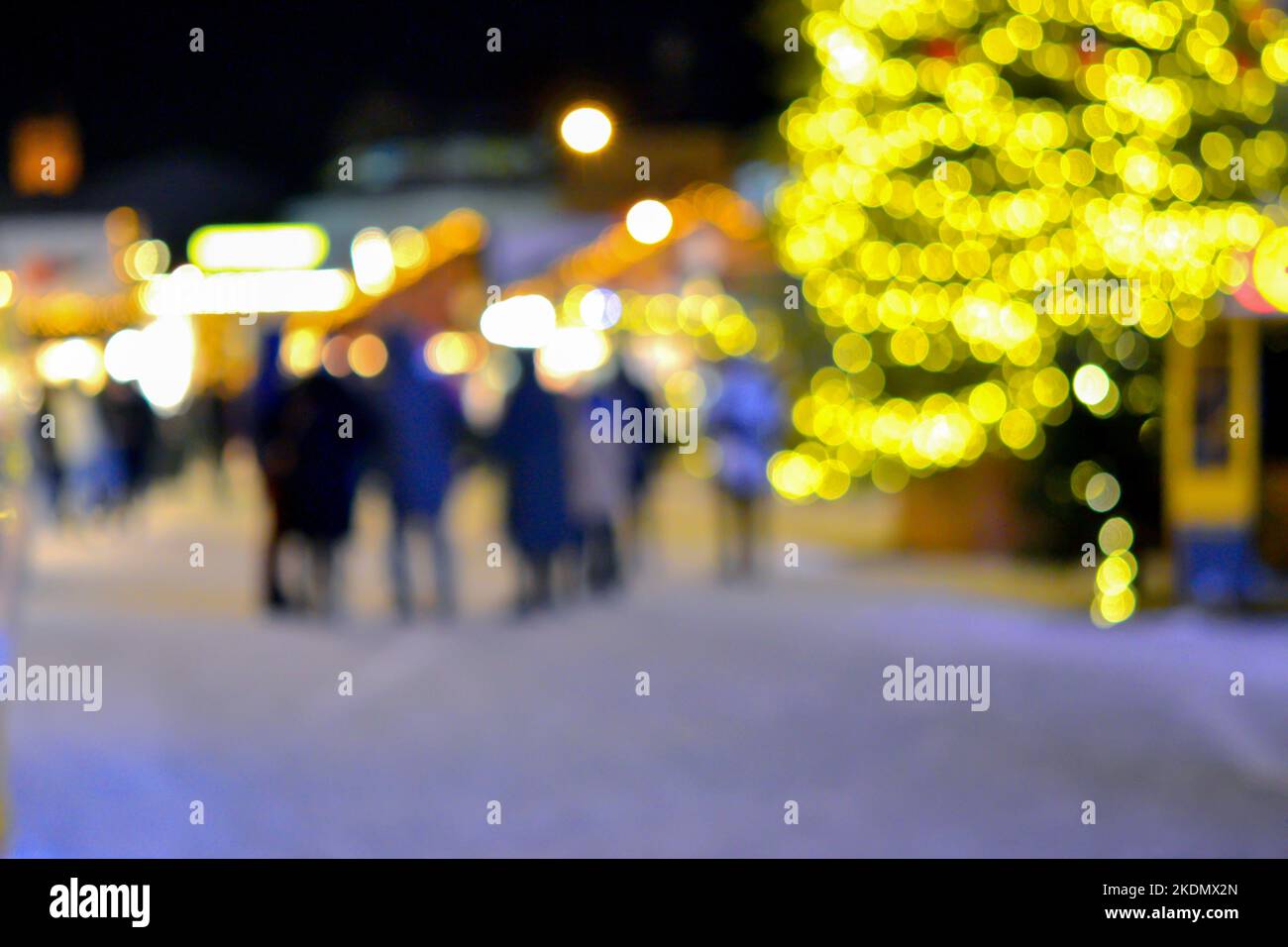 Sfondo sfocato. Albero di Natale, luci decorate, edificio, sagome sfocate di persone che camminano piazza della città durante la notte d'inverno. Bello Capodanno e Natale vacanza sfondo sfocato Foto Stock