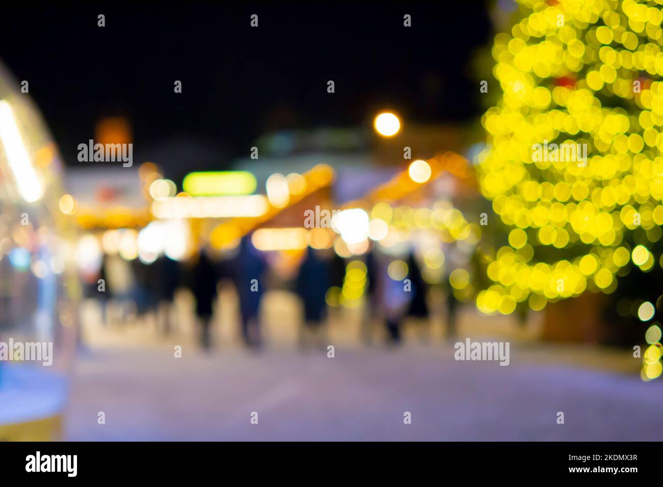 Sfondo sfocato. Albero di Natale, luci decorate, edificio, sagome sfocate di persone che camminano piazza della città durante la notte d'inverno. Bello Capodanno e Natale vacanza sfondo sfocato Foto Stock