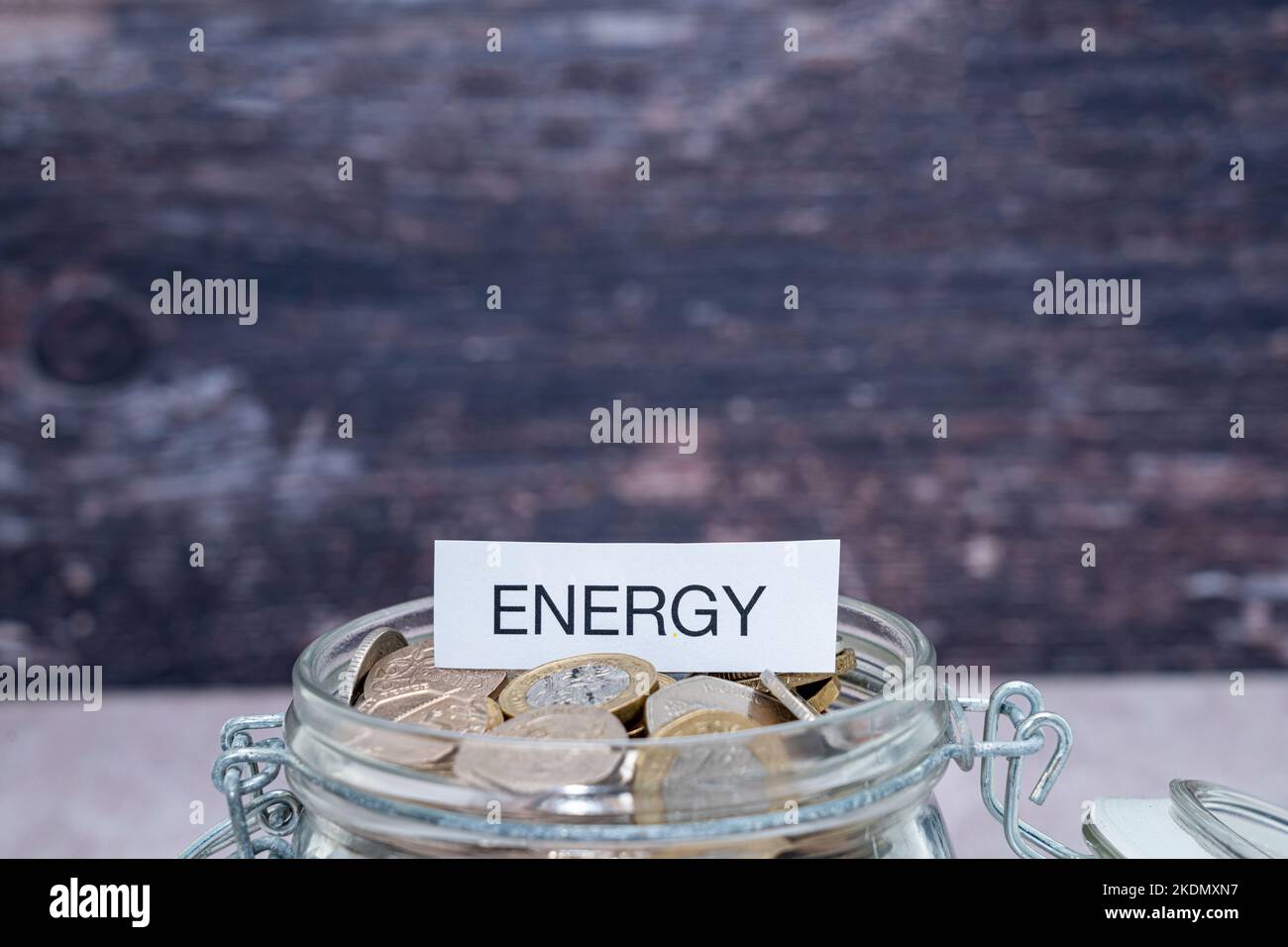 Un'etichetta di carta con la parola energia sulla parte superiore di un vasetto di risparmio di vetro delle monete Foto Stock