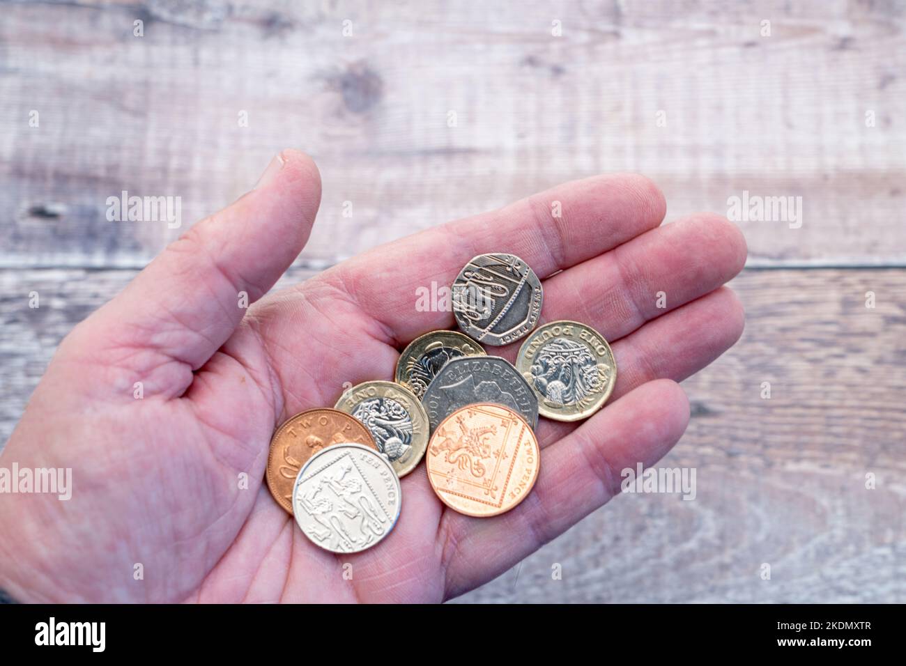 Un uomo anziano che tiene fuori la sua mano contenente alcune monete - Regno Unito Foto Stock