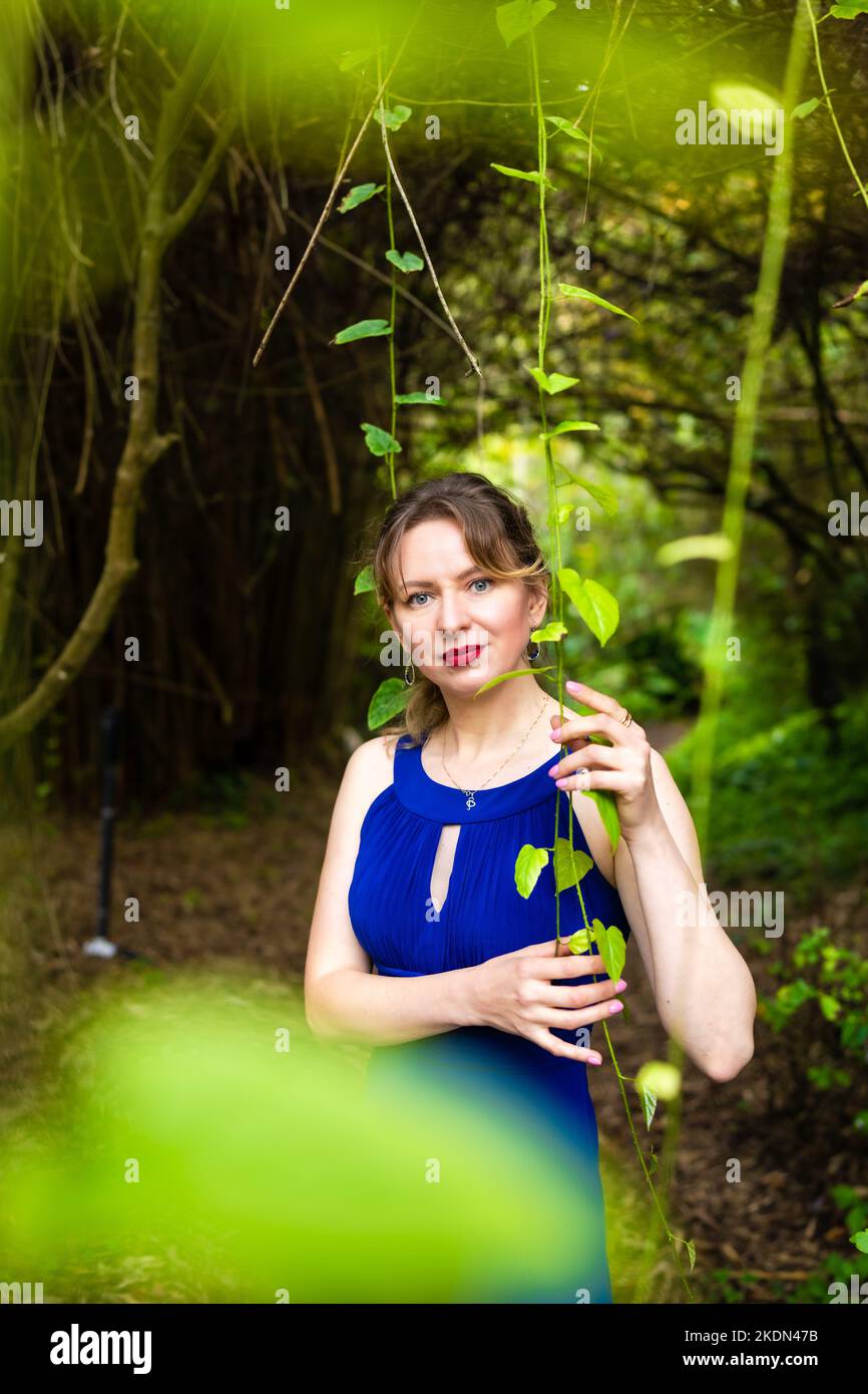 Donna che indossa una abito blu in visita a un giardino botanico Foto Stock
