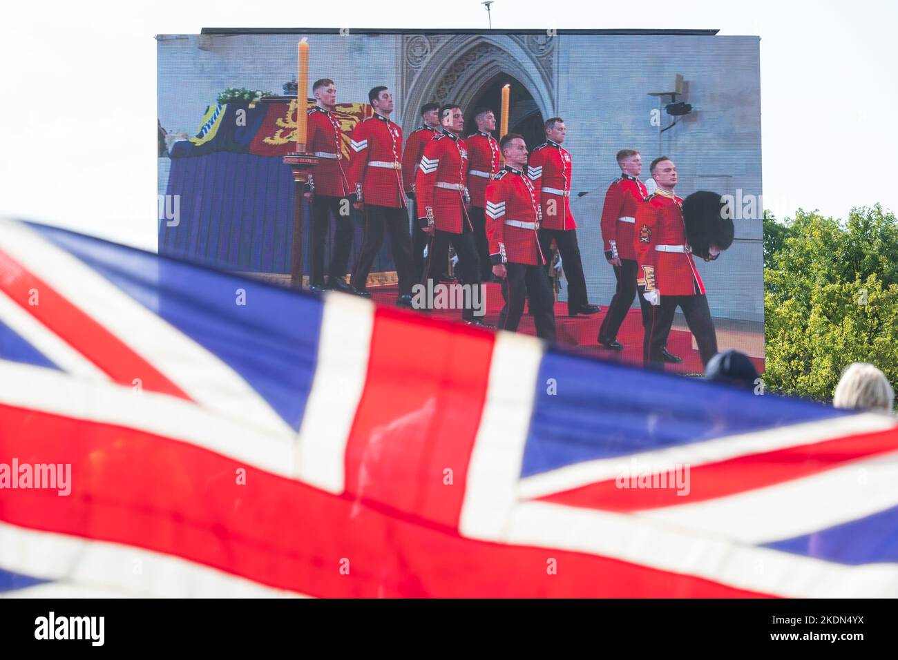 Una coppia che tiene una bandiera di Union Jack mentre guardano la trasmissione dal vivo della Una coppia che tiene una bandiera di Union Jack mentre guardano la trasmissione dal vivo della
