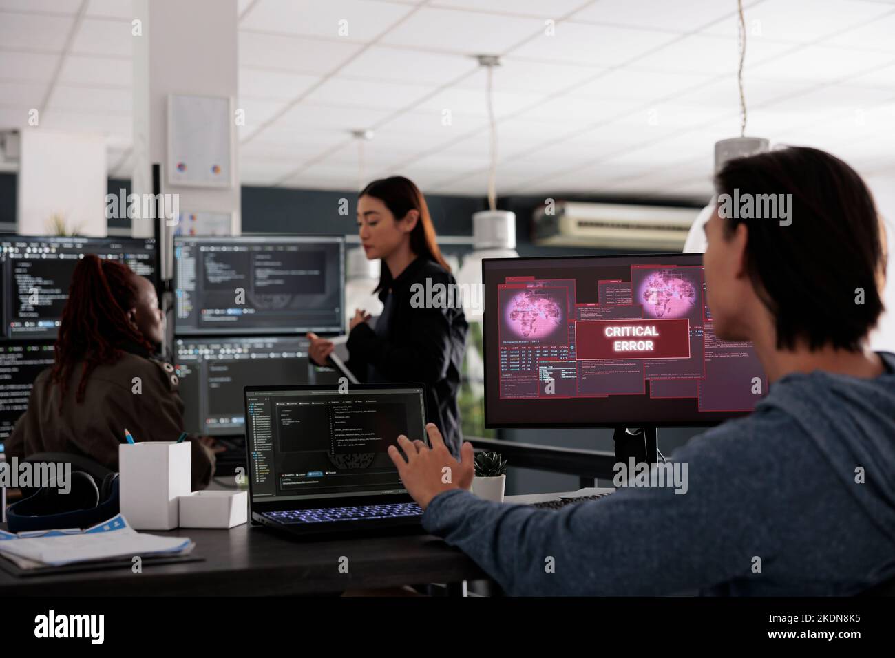 Il tecnico IT sta esaminando l'errore critico di lettura del monitor nell'agenzia IT per i big data, che viene violato. Sviluppatore di app che lavora con codice di intelligenza artificiale e database server per fermare l'hacking del programma. Foto Stock