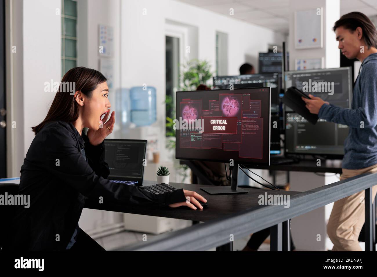 Sviluppatore di app asiatico che ha violato il server Web, analizzando l'errore critico sulla programmazione del monitor del computer in ufficio. Sviluppatore di software che tenta di risolvere il problema di hacking, firewall di sicurezza. Foto Stock