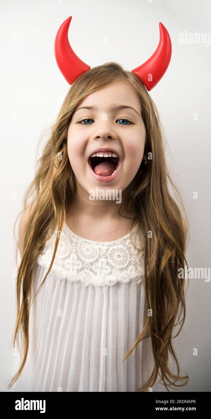 bella bambina carina con corna rosse in posa e sorridente alla fotocamera Foto Stock