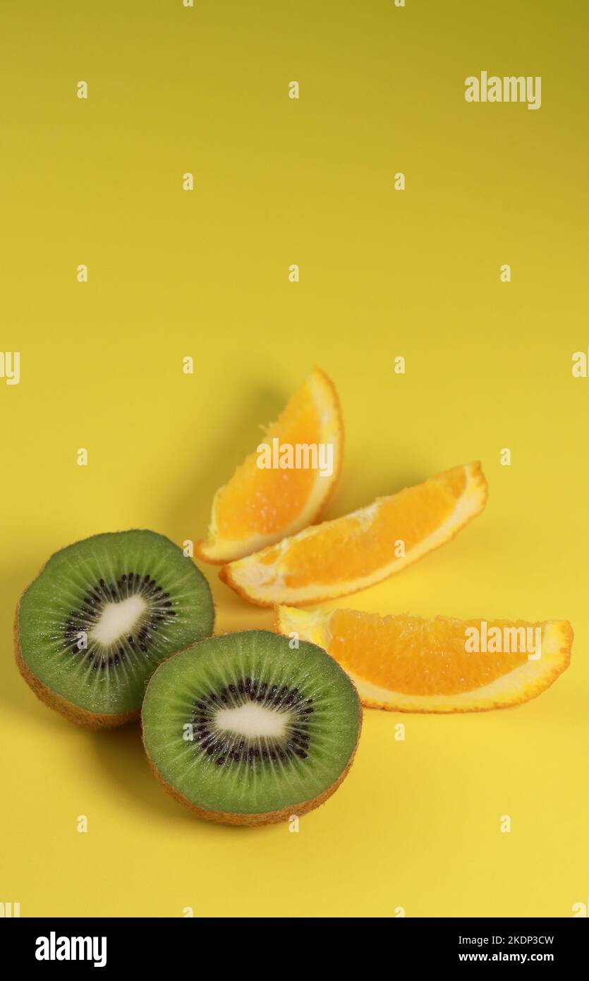 primo piano di kiwi e fette di arancia su sfondo giallo Foto Stock
