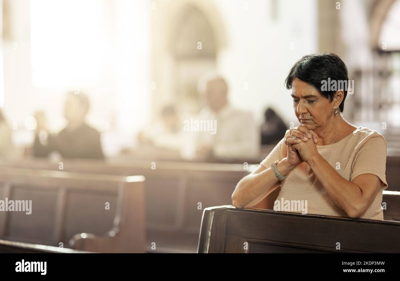 Donna anziana che prega in chiesa, adorare e fidarsi di Dio, la preghiera o il rispetto spirituale. La donna cristiana lode nel tempio santo della religione, della fede e. Foto Stock