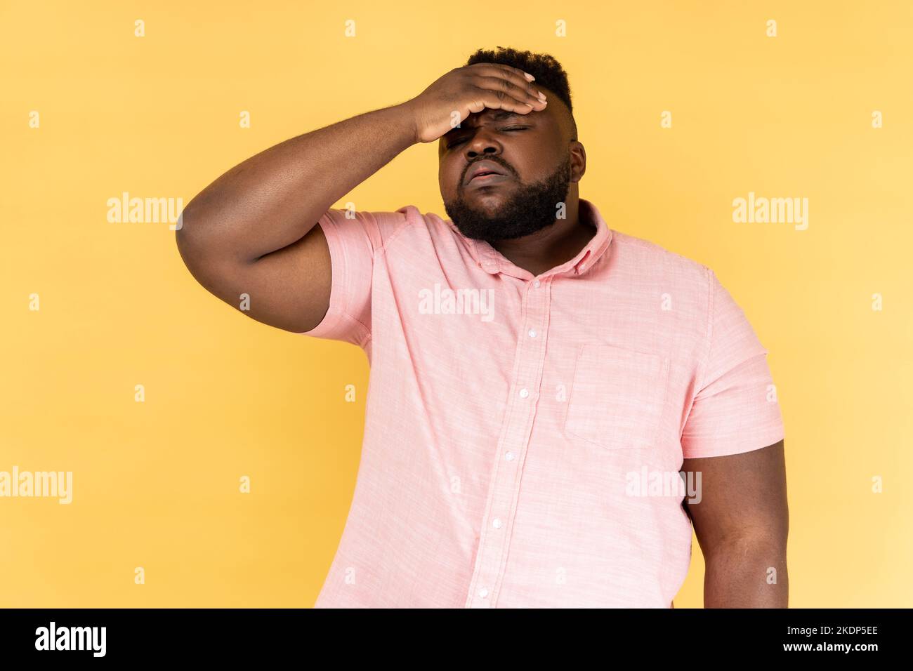 Facepalm. Ritratto di uomo bearded che indossa una camicia rosa che schiaffa la mano sulla fronte, sentimento di dolore rammarico per l'evento dimenticato, memoria difettosa. Studio al coperto isolato su sfondo giallo. Foto Stock