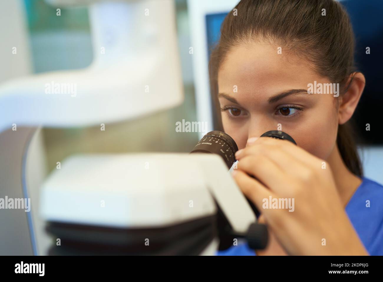 Vediamo cosa abbiamo qui: Un giovane patologo che guarda i campioni al microscopio. Foto Stock
