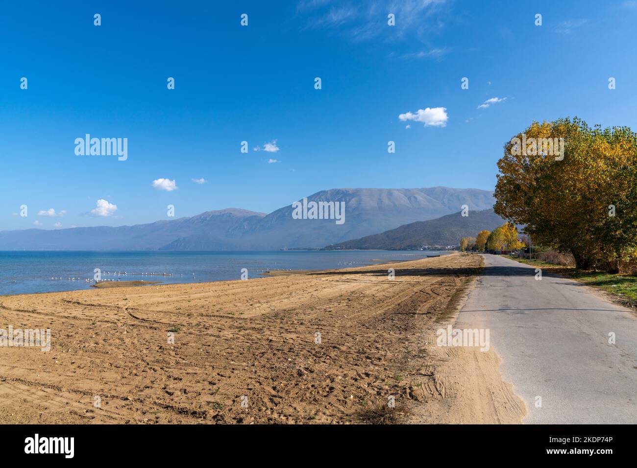 Una vista sulla spiaggia di Pogradec e sulle montagne sulle sponde meridionali del Lago Ohrid in Albania Foto Stock