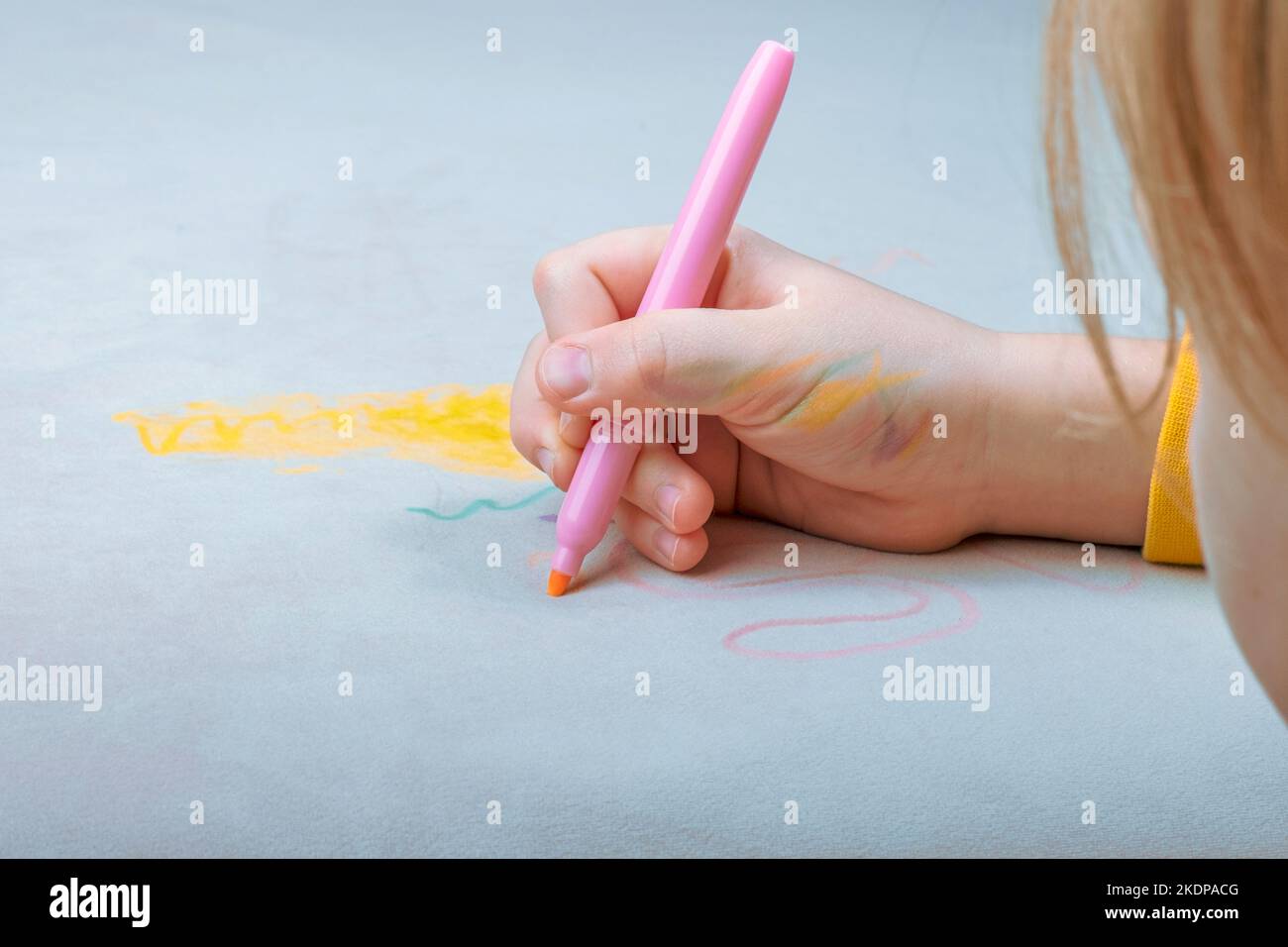 Il disegno a mano del bambino con penna in feltro rosa sul rivestimento grigio del lettino. La vita quotidiana macchia sporca per il lavaggio e il concetto di pulizia Foto Stock