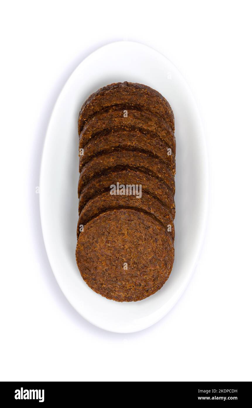Fettine di pumpernickel in una ciotola bianca. Dischi a forma di cerchio di un pane di segale pesante, leggermente dolce, marrone scuro, tradizionalmente preparato con pasta madre. Foto Stock