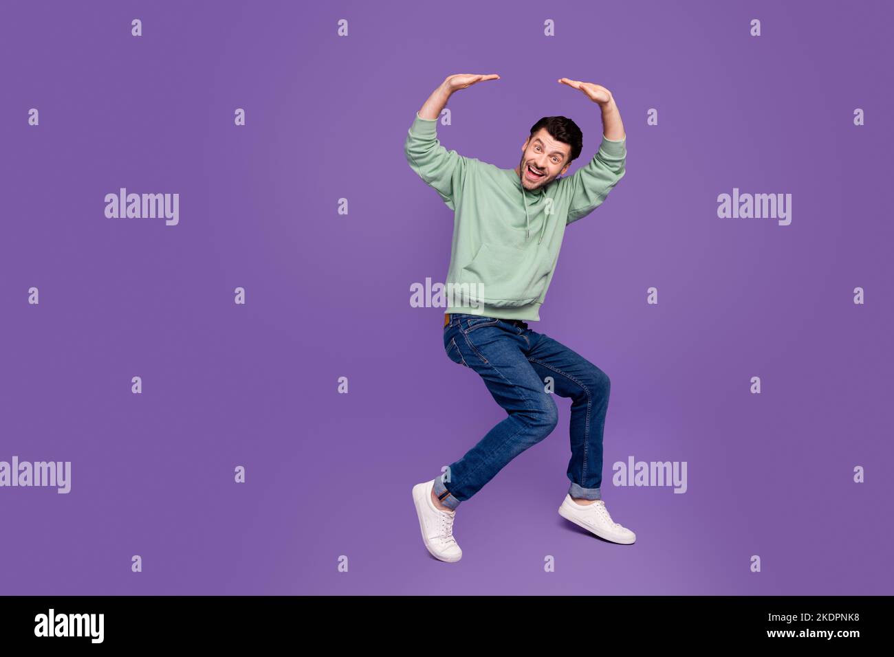 Foto a tutta lunghezza di bel giovane uomo tenere caduta pesante spazio vuoto indossare trendy grigio isolato su sfondo di colore viola Foto Stock