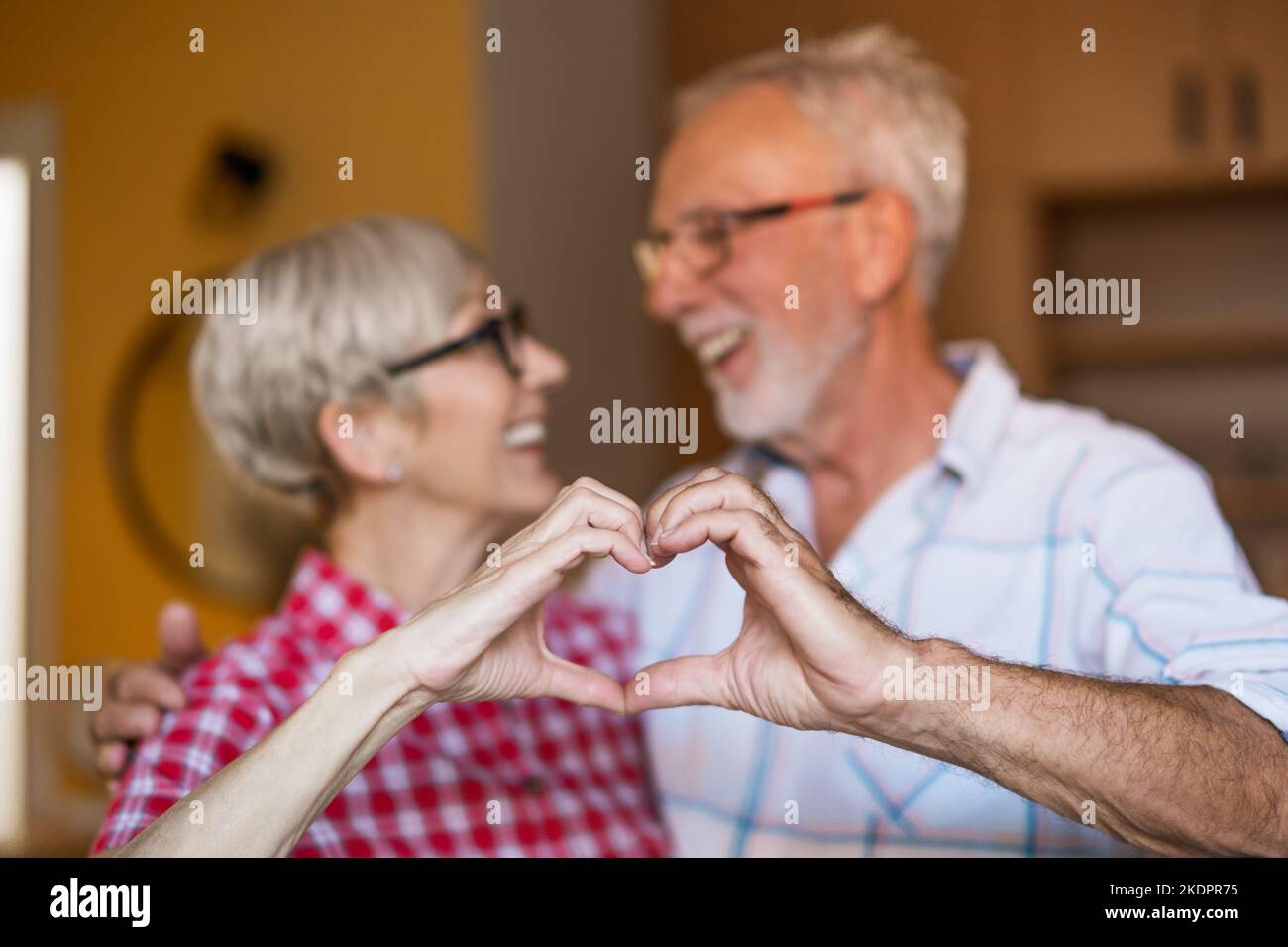 Coppia anziana felice sta abbracciando e facendo la figura del cuore con le loro mani. Foto Stock