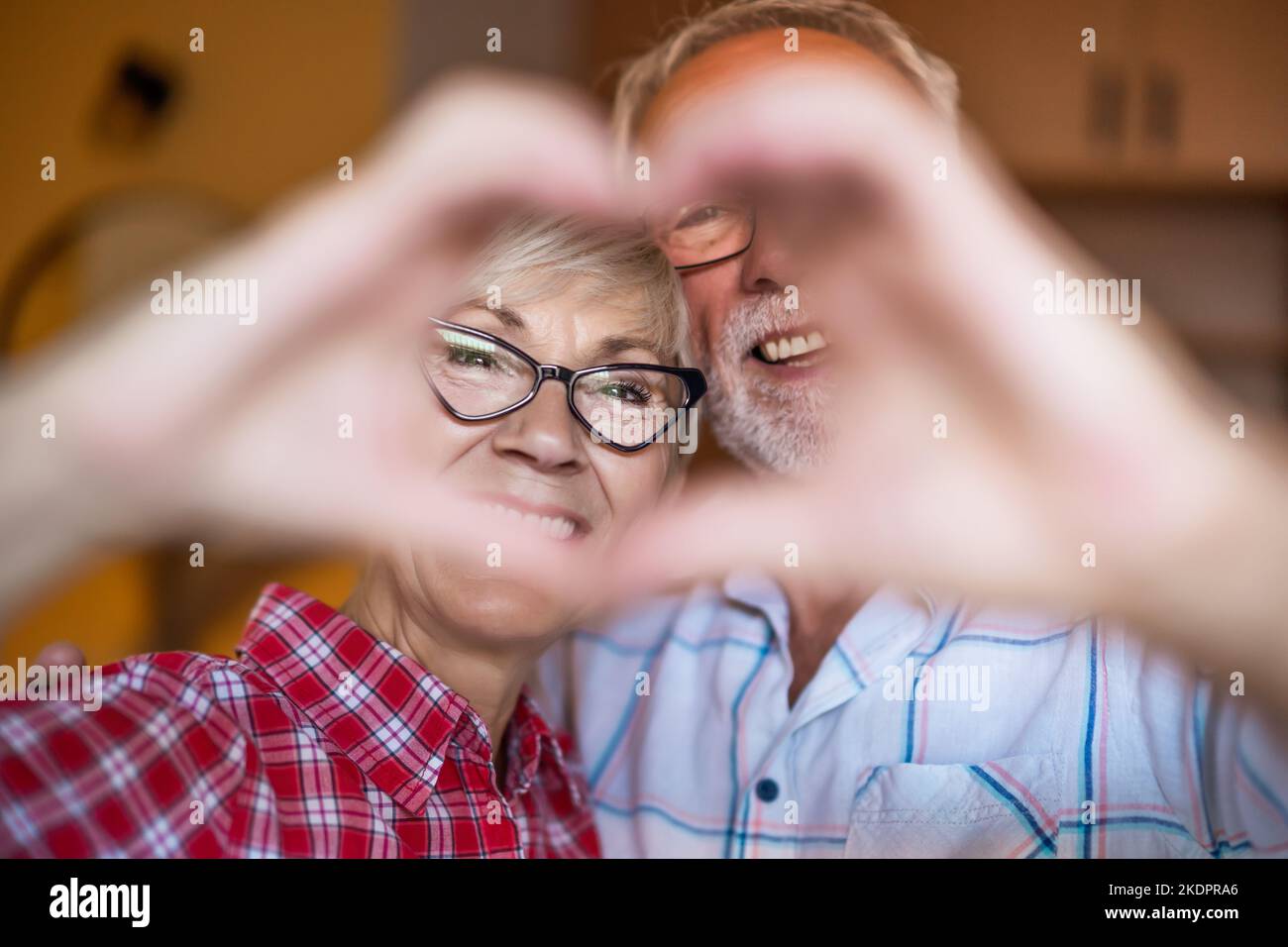 Coppia anziana felice sta abbracciando e facendo la figura del cuore con le loro mani. Foto Stock