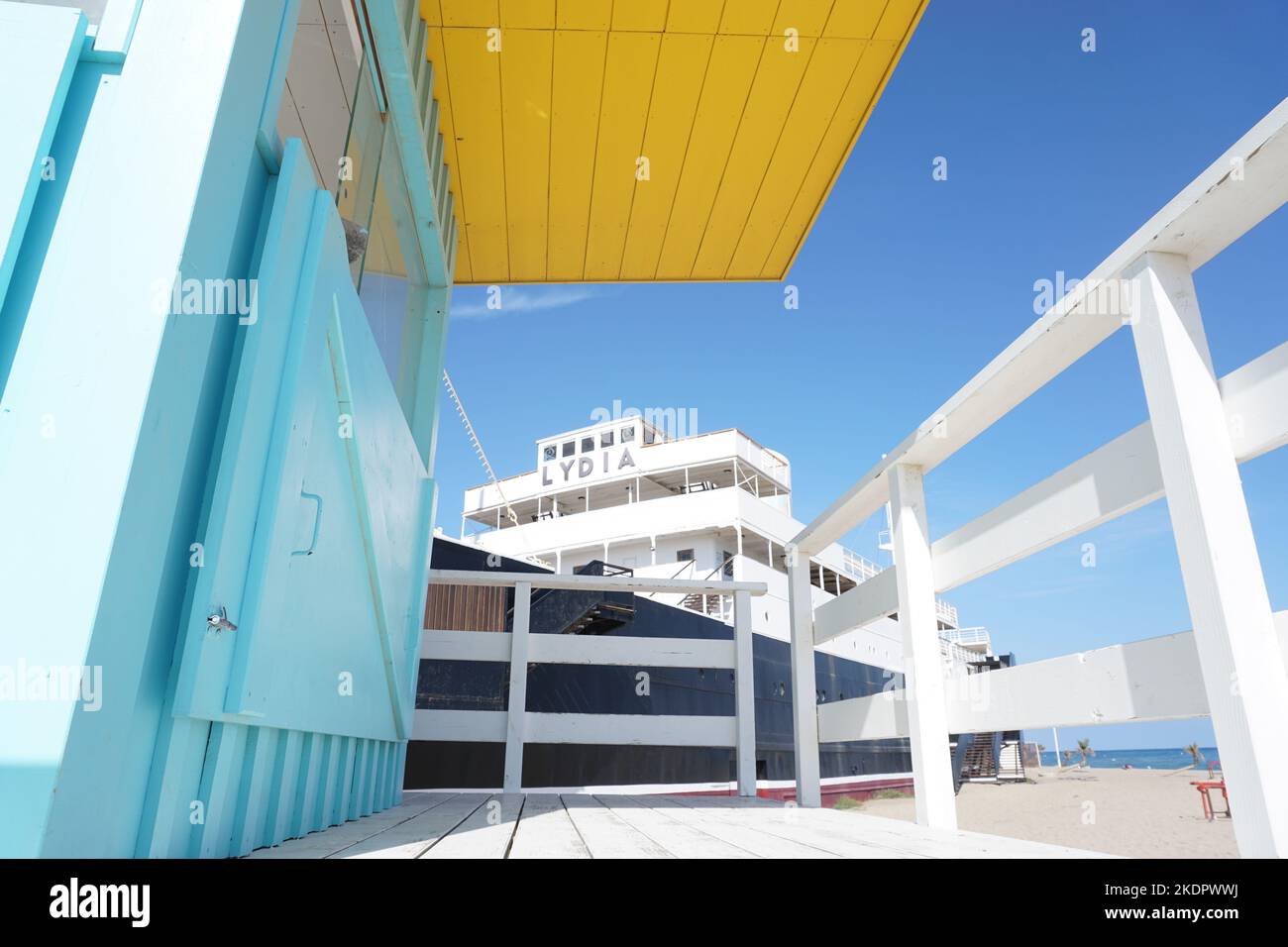 Port-Barcarès, Francia - 2022 ottobre; ex nave da crociera le Lydia sulla spiaggia vista da una torre di bagnino dai colori vivaci sullo sfondo del cielo blu Foto Stock