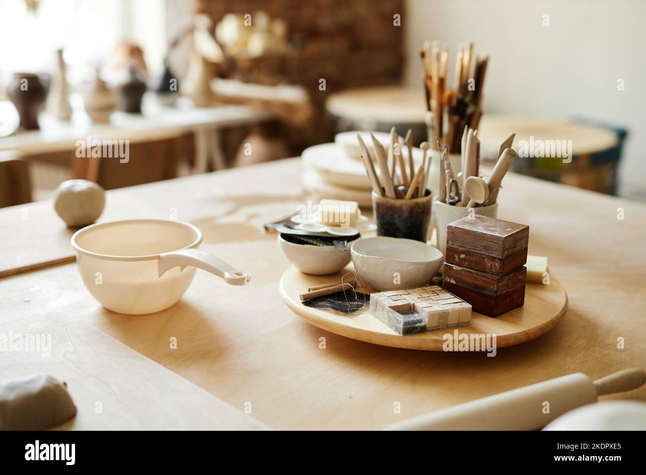 Immagine di sfondo di vita morta di tazze in ceramica e forniture d'arte sul tavolo in accogliente studio di ceramica, copia spazio Foto Stock