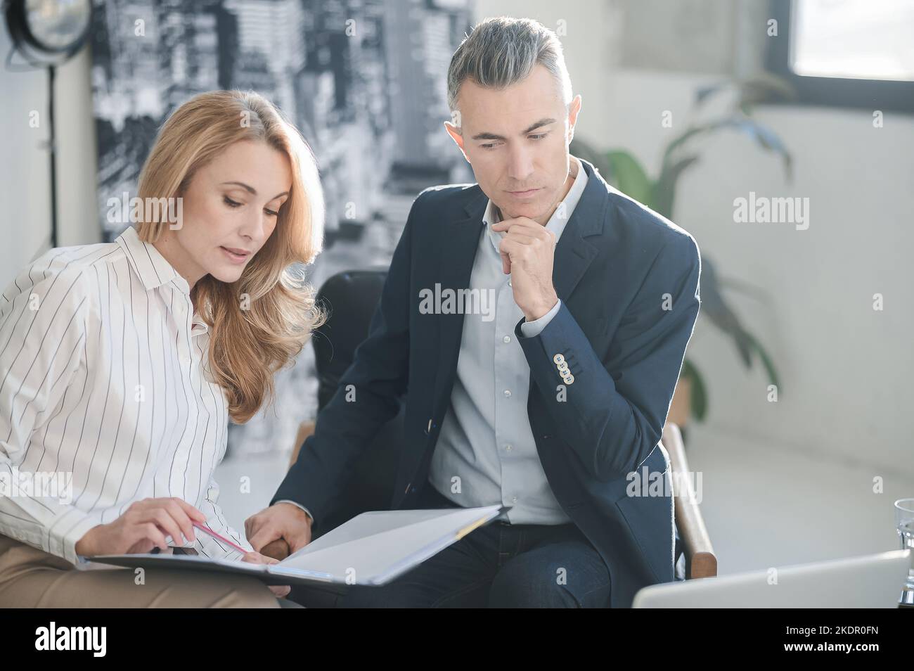 Un uomo e una donna che lavorano insieme in ufficio e che guardano coinvolti Foto Stock