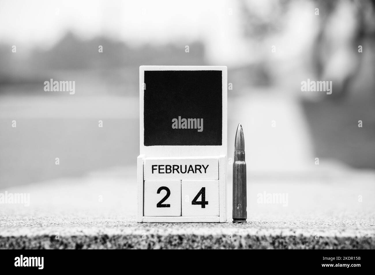 Calendario in legno con la data 24 febbraio, il primo giorno della guerra in Ucraina e una pallottola si trova sulla strada della città, data storica, guerra 2022 Foto Stock
