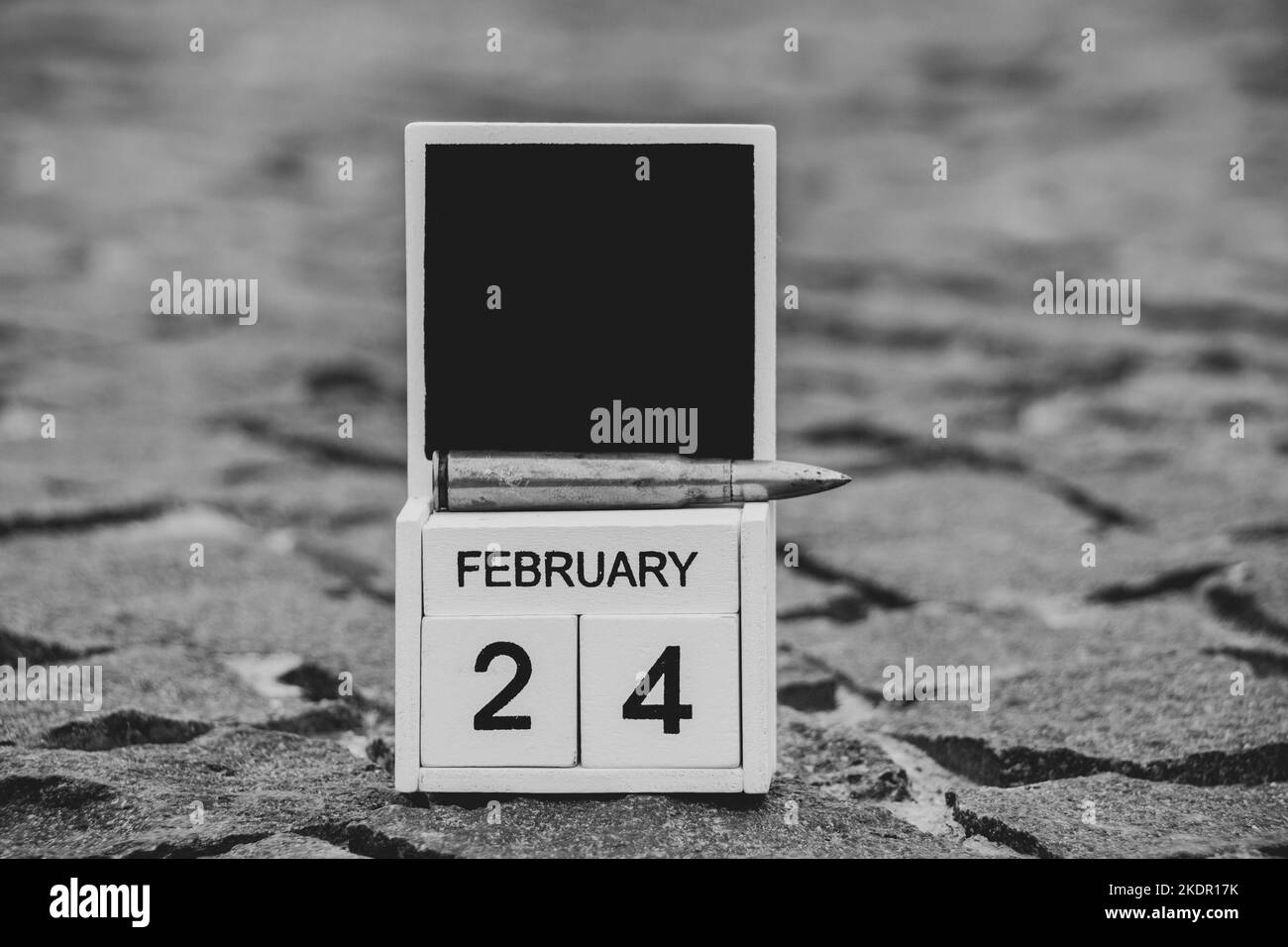 Calendario in legno con la data 24 febbraio, il primo giorno della guerra in Ucraina e una pallottola si trova sulla strada della città, data storica, guerra 2022 Foto Stock