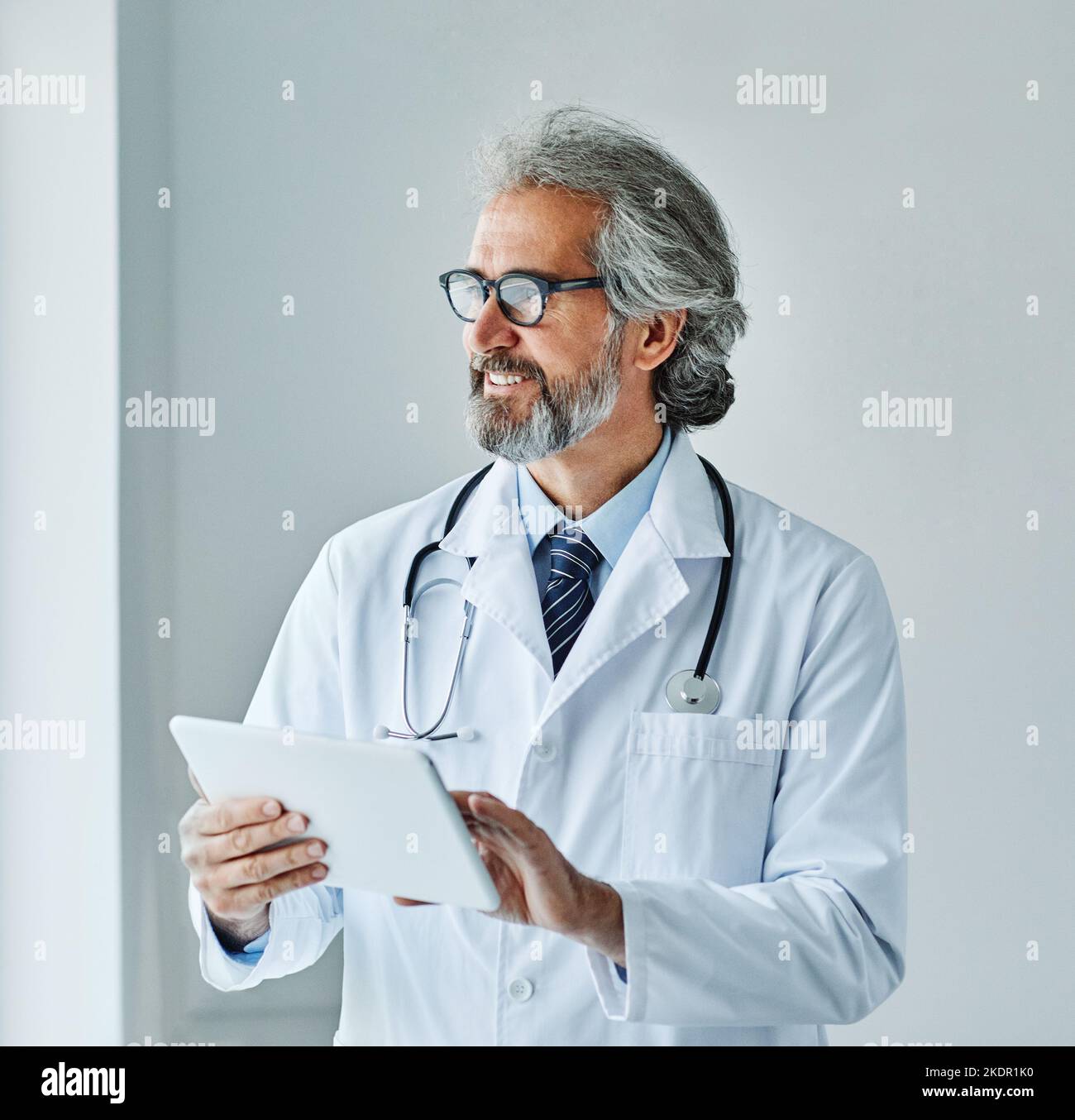 anziani capelli grigi attivi medico ospedale medicina salute clinica ufficio ritratto occhiali uomo stetoscopio specialista tablet computer Foto Stock