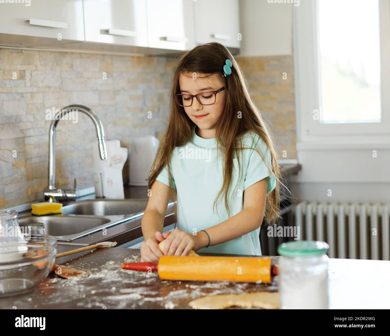 bambino ragazza cucina cottura cibo farina pasta preparazione ingrediente cottura pasticceria fatta in casa uovo cuoco infanzia forno casa grembiule torta Foto Stock