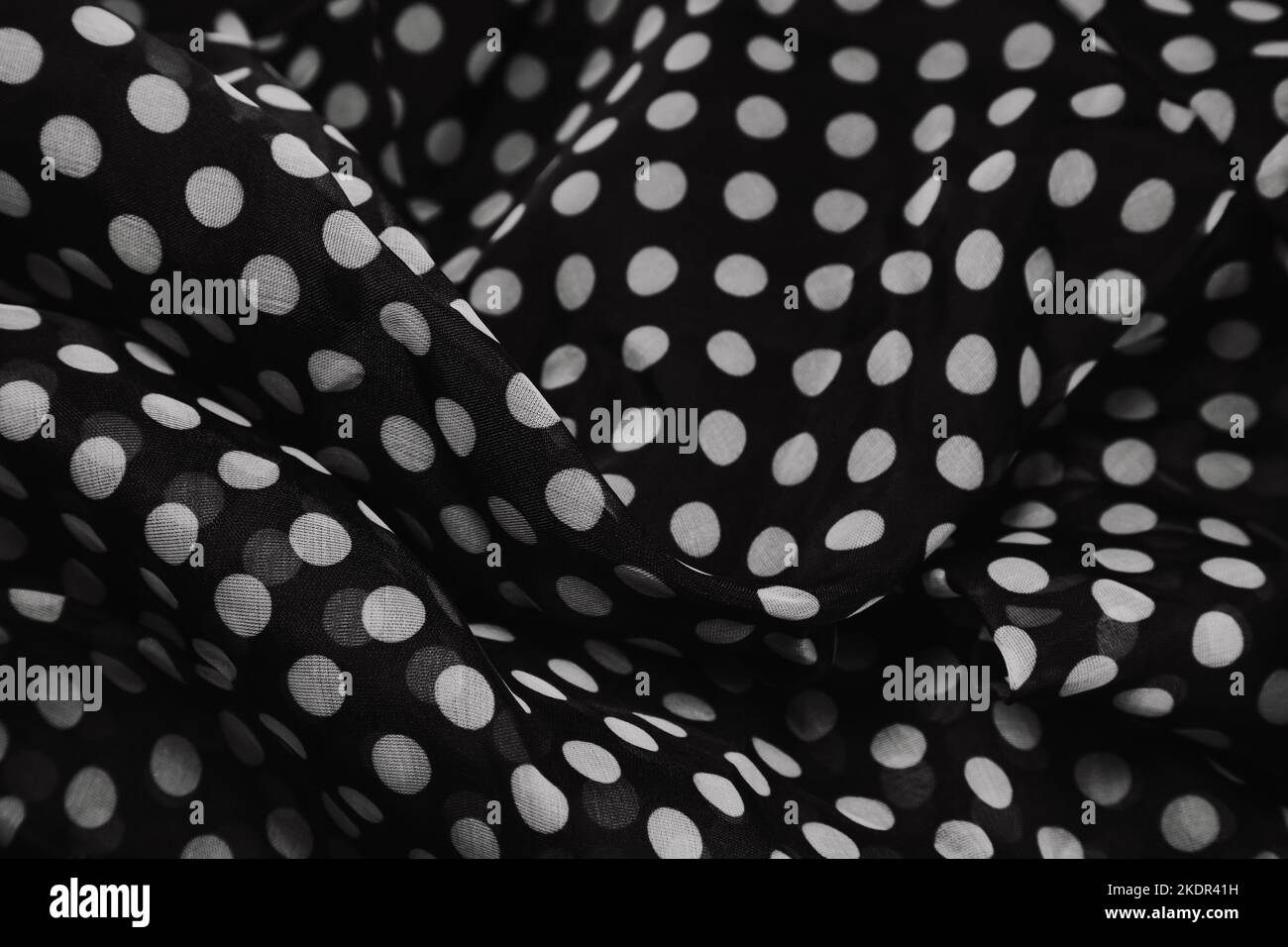 Tessuto raccolto e piegato di polka bianco e nero stampa punto copia spazio.pieghe formano una texture nero ondulato. Concetto di fotografia in stile retrò. Foto Stock
