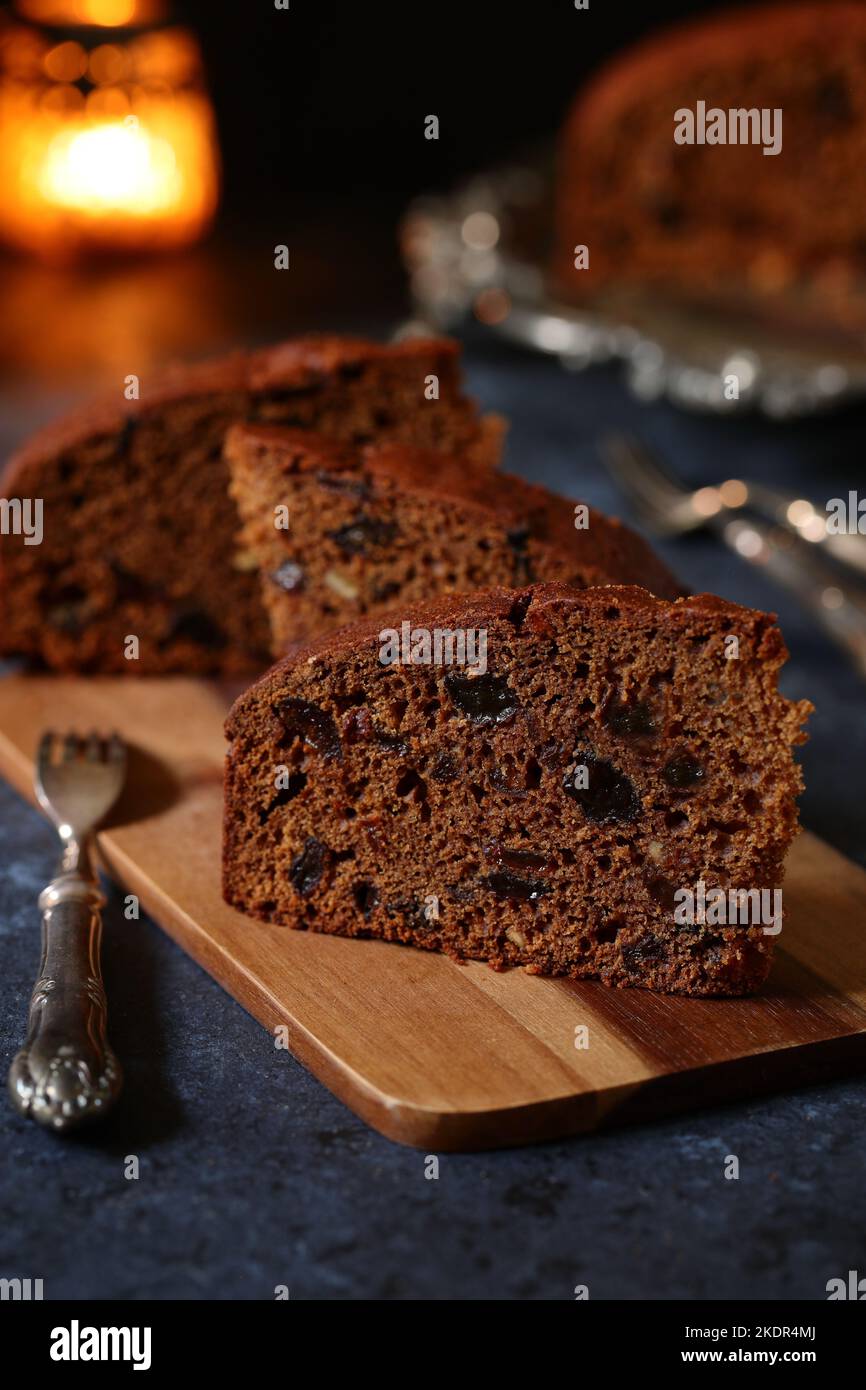 Fette di frutta tradizionale fatta in casa e torta Guinness su un piatto d'argento decorativo d'annata con forchette da dessert decorative e lume di candela Foto Stock