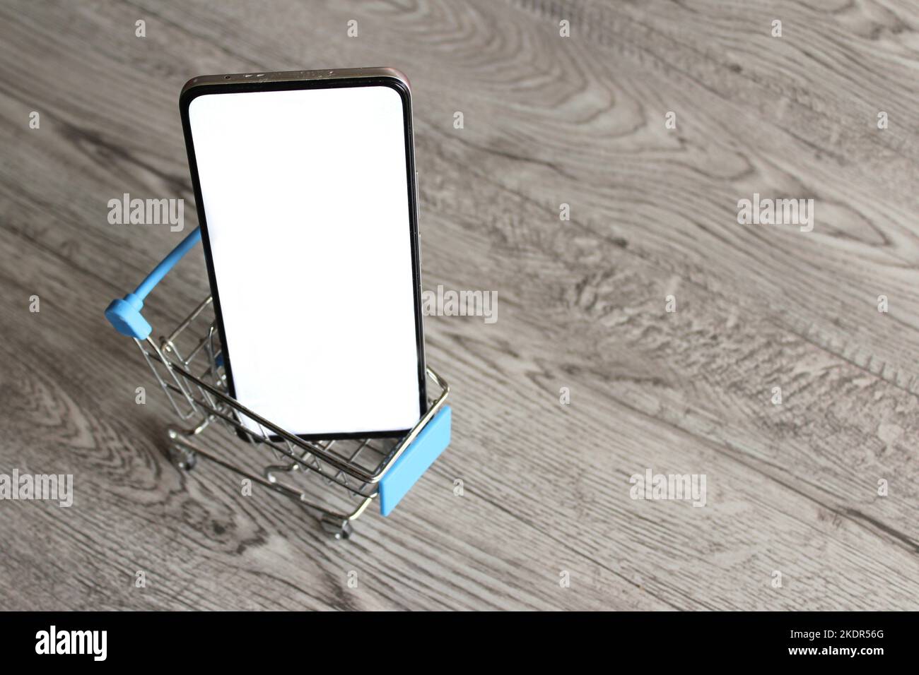 Smartphone con schermo bianco vuoto all'interno del carrello della spesa con spazio per le copie. Concetto di shopping mobile Foto Stock