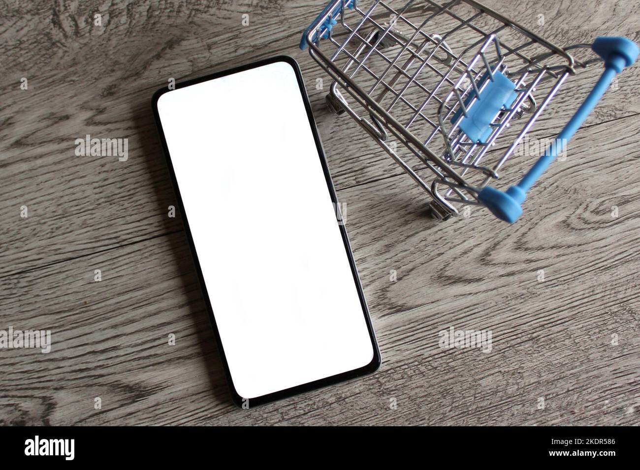 Smartphone con schermo bianco vuoto all'interno del carrello della spesa con spazio per le copie. Concetto di shopping mobile Foto Stock