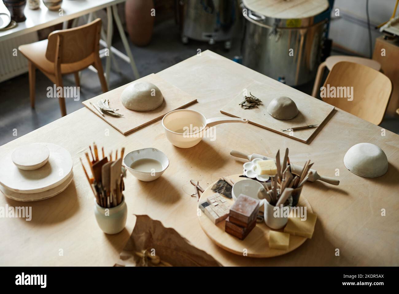 Immagine di sfondo ad angolo alto di argilla e forniture d'arte sul tavolo in accogliente studio di ceramica, copia spazio Foto Stock