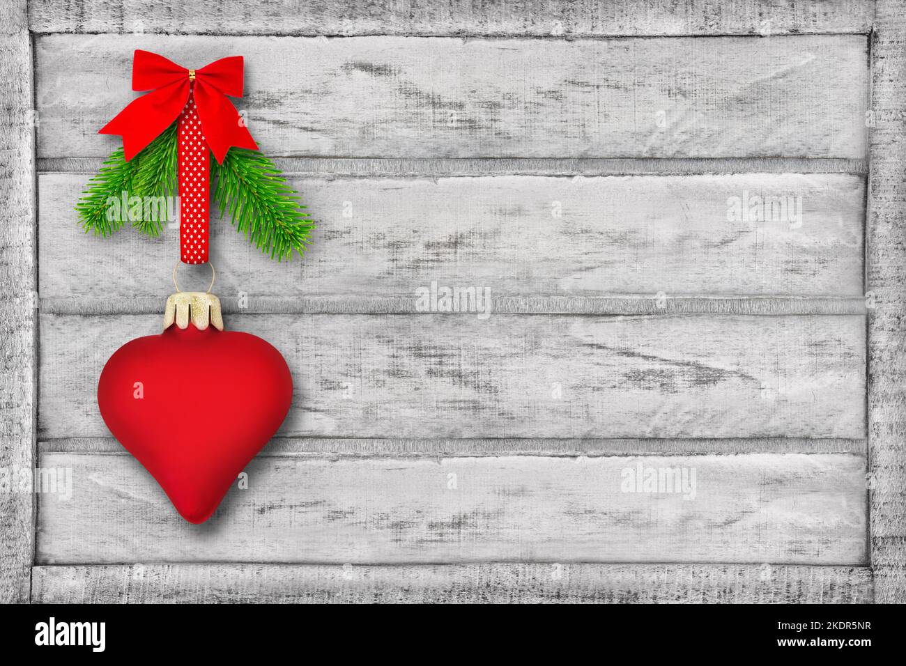 Decorazione natalizia con cuore rosso e rami di abete su fondo in legno Foto Stock