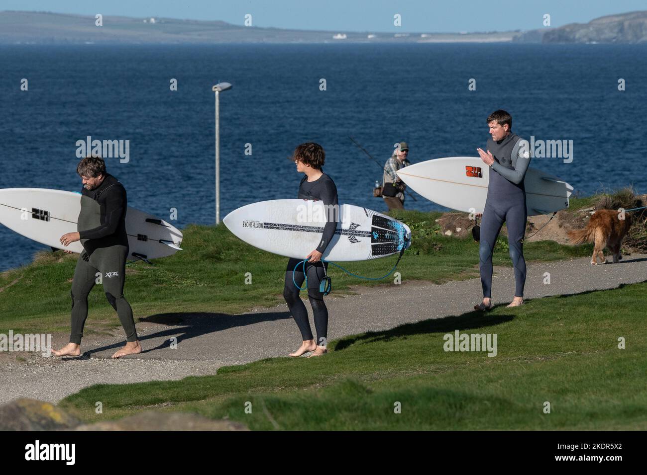 Tre surfisti che trasportano le loro tavole da surf e camminano lungo il sentiero costiero a Newequay in Cornovaglia in Inghilterra nel Regno Unito. Foto Stock