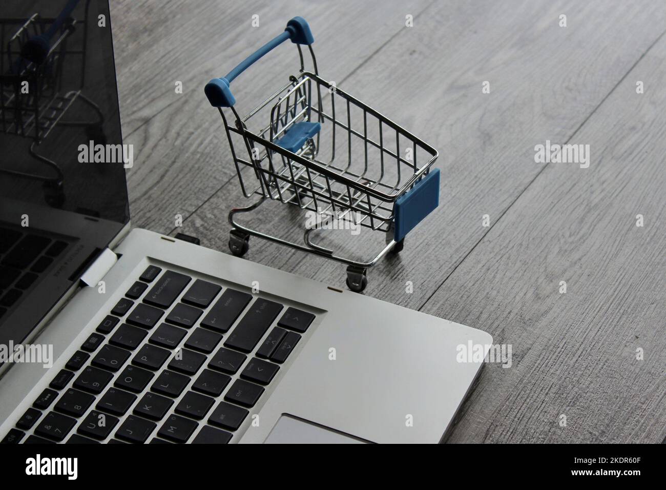 Portatile e mini carrello su tavolo di legno. Concetto di shopping online Foto Stock