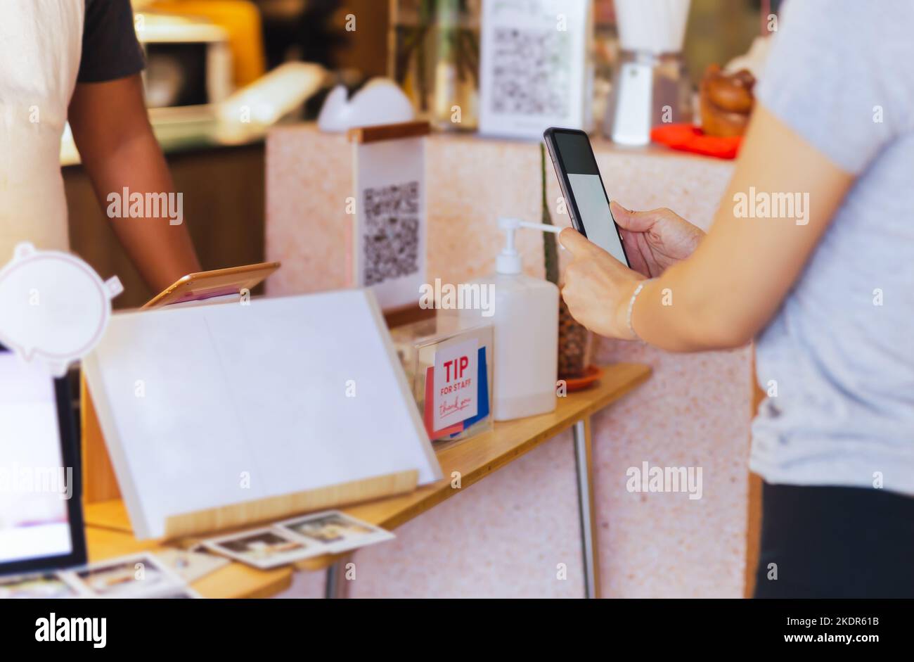 Donne clienti asiatici che pagano tramite la scansione del codice QR sul telefono cellulare presso la caffetteria. Foto Stock