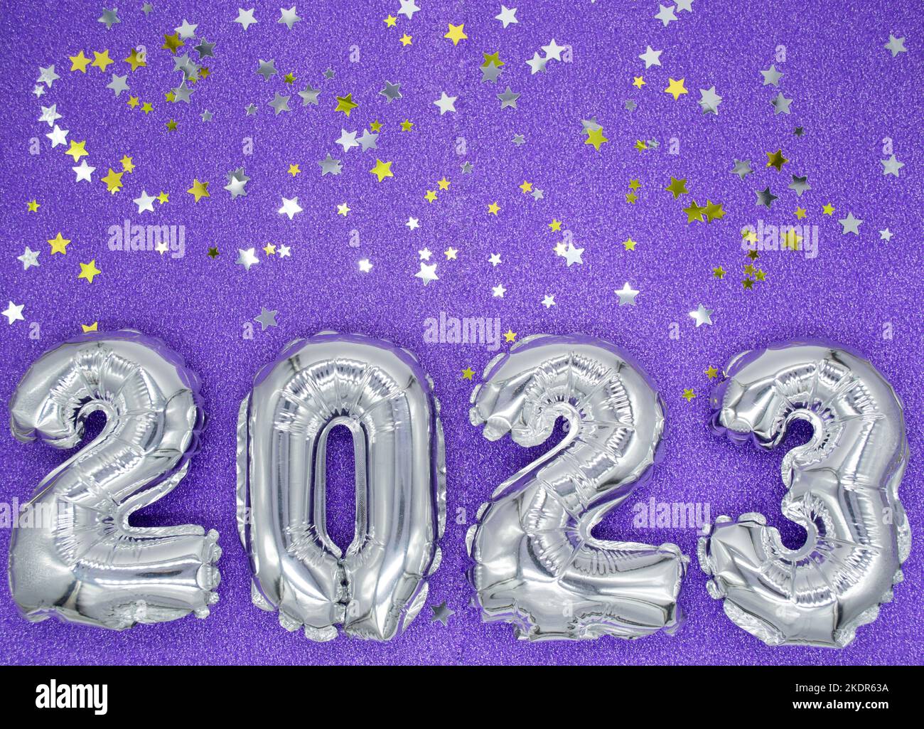 Numeri gonfiabili in argento lucido del nuovo anno 2023 su sfondo di colore viola, molto peri con stelle dorate e argento lucenti. Spazio di copia. Foto Stock