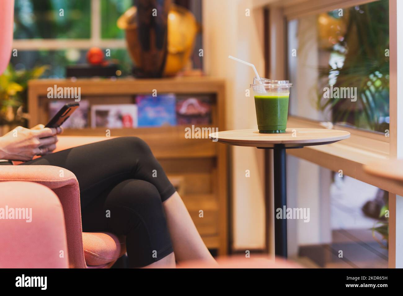 Moman bere sano verde morbido e utilizzando smartphone in caffè. Foto Stock