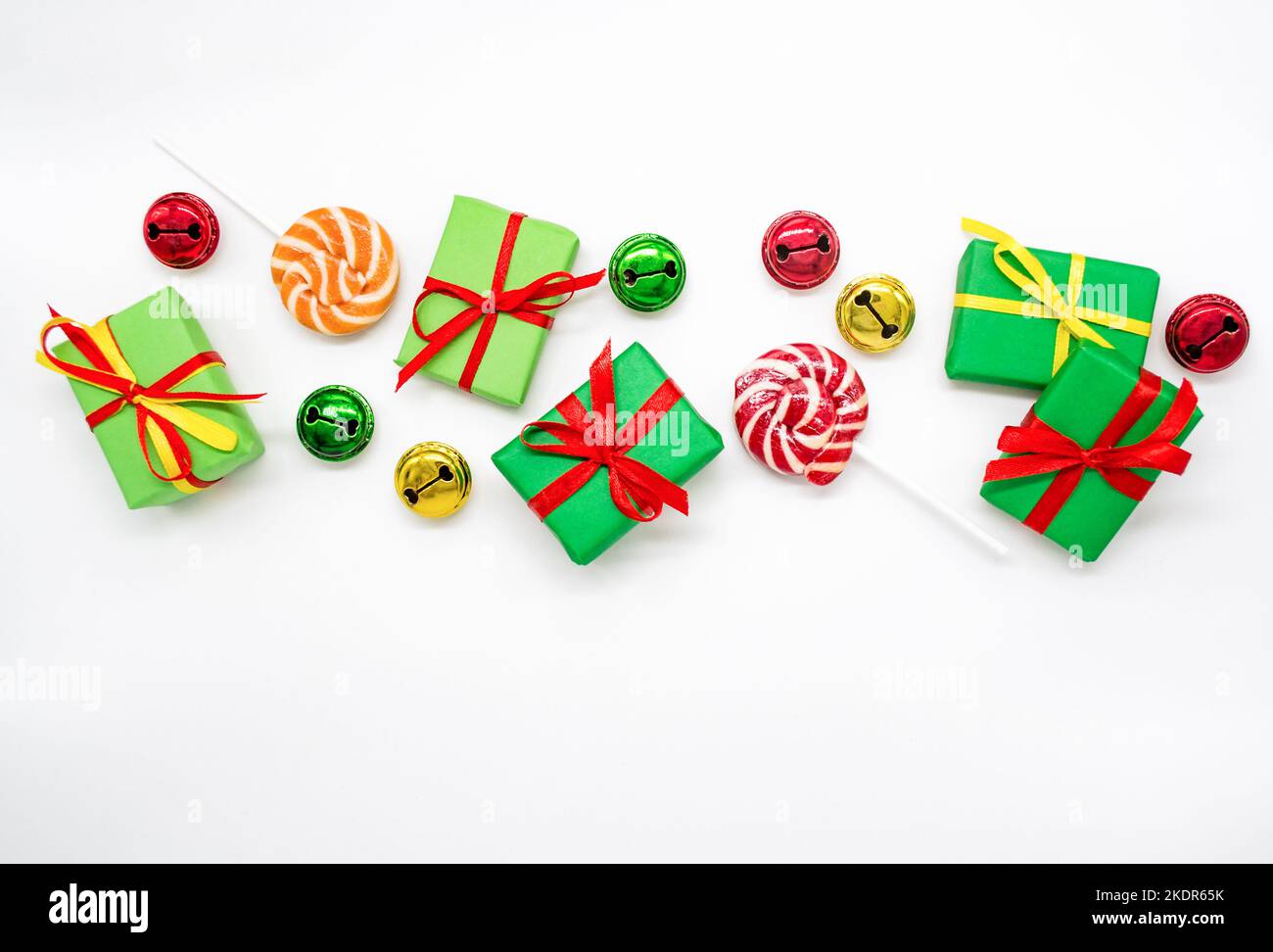 Buone feste: Regali con lollipop e campane rosse, verdi, dorate su sfondo bianco, spazio copia. Il concetto di Natale, le vendite, le feste dei bambini Foto Stock