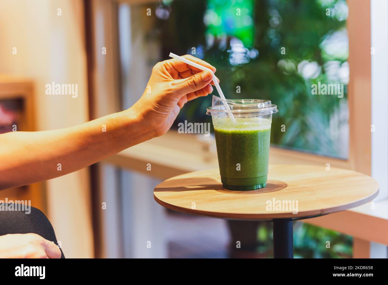 Sana dieta concetto donna bere frullato verde in caffè. Foto Stock