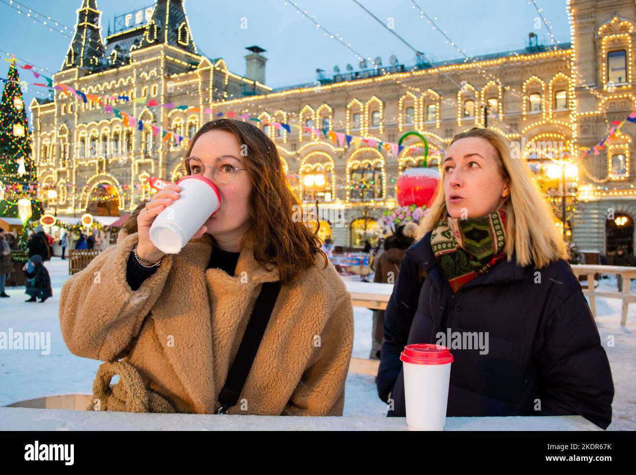 Due giovani donne bevono VIN brulé con tazze di cartone. Fiera di Natale sulla Piazza Rossa, Mosca. Foto Stock