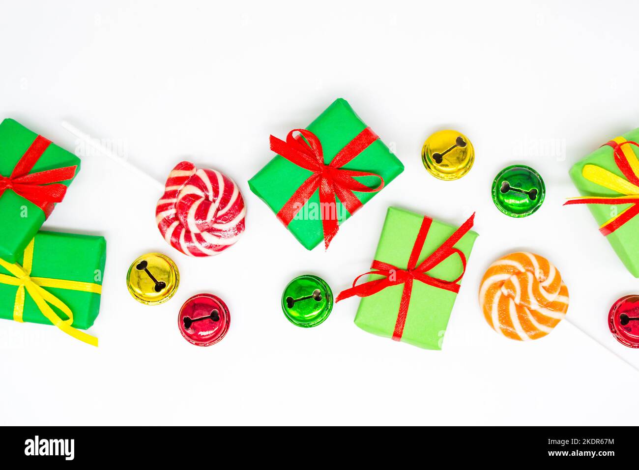 Buone feste: Regali con lollipop e campane rosse, verdi, dorate su sfondo bianco, spazio copia. Il concetto di Natale, le vendite, le feste dei bambini Foto Stock